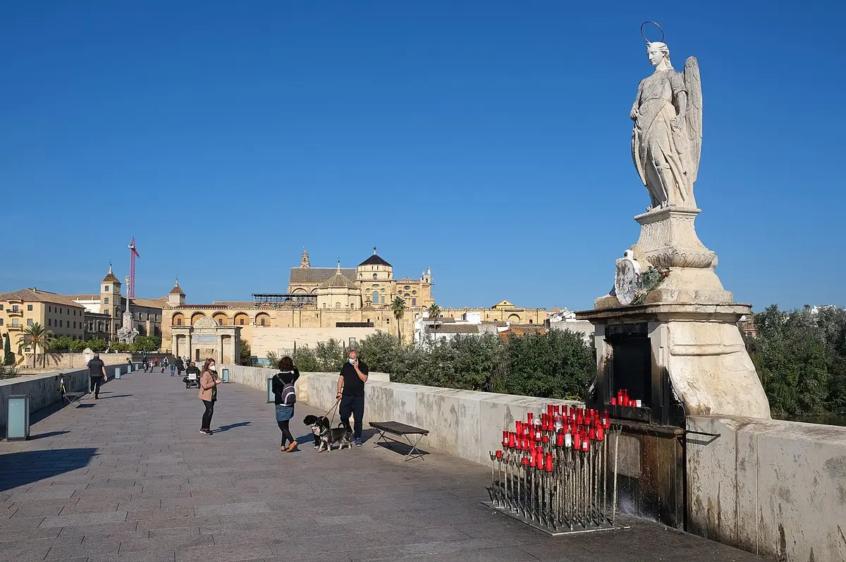 Paseo del Puente Romano de Córdoba con la estatua de un ángel y, al fondo, la Mezquita-Catedral