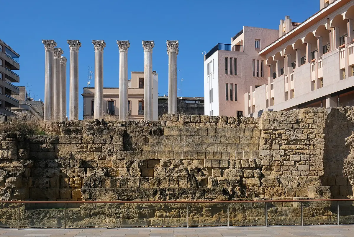 Siete columnas del Templo Romano de Córdoba sobre un basamento de piedra, con edificios modernos al fondo